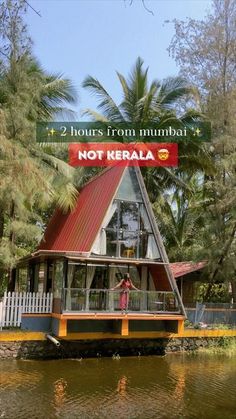 a house boat floating on top of a lake next to palm trees and a sign that says, 2 hours from mumbai not kerala