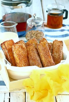 bread sticks are in a white dish on a table with flowers and other food items