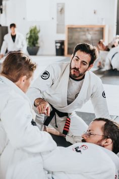 two men sitting on the ground while one man in white is holding his hand out