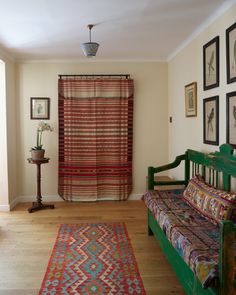 a room with a couch, rug and pictures on the wall in it's corner