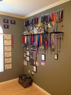 there is a wall with many medals hanging on it and a bag in the corner