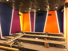 an empty auditorium with multiple rows of seats in front of colorful walls and ceiling lights