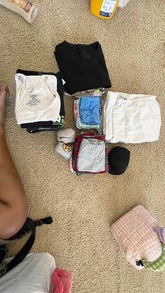 a person laying on the floor next to some clothes and other items that have been placed around them