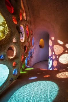 the interior of a rock house with colorful glass windows and sunlight coming in from behind