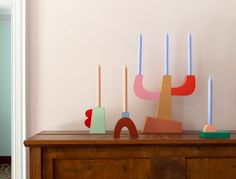 a wooden dresser with candles on top of it in front of a wall mounted art piece