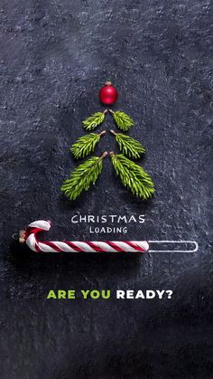 a candy cane sitting on top of a black surface next to a christmas tree and the words, are you ready?