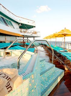 an outdoor jacuzzi pool on the deck of a cruise ship with sun umbrellas