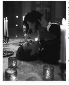 a woman laying on the floor next to a man with candles in front of her