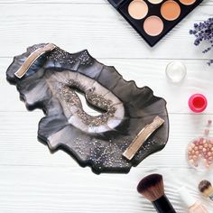 various cosmetics and makeup products on a white table with an eye shadow, brush, eyeshade, palettes