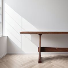 a wooden table sitting on top of a hard wood floor next to a white wall