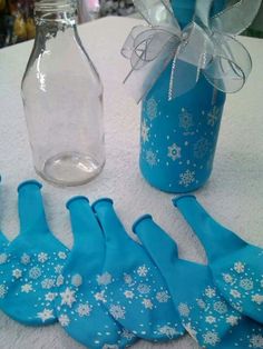 blue snowflaked mitts are sitting on a table next to a glass bottle