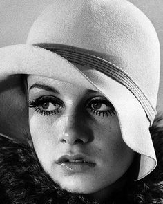 black and white photograph of a woman wearing a hat with large lashes on her face