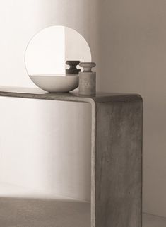 a white bowl sitting on top of a metal table next to a mirror and vase