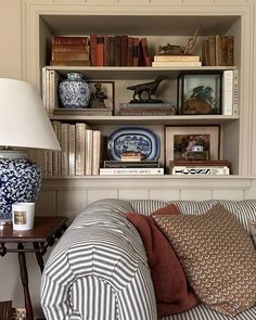 a living room filled with furniture and bookshelves next to a lamp on a table