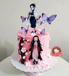 a pink cake with an image of a woman and butterflies on the top, sitting on a table