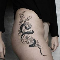 a woman's thigh with a snake and flowers tattoo on the side of her leg