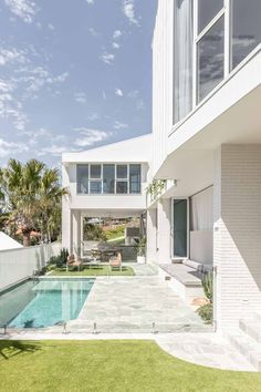 an outdoor swimming pool next to a white house