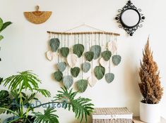 a wall hanging made out of leaves next to a potted plant on a table