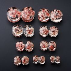 a collection of pink flowers in glass containers on a black surface with spacers to insert them