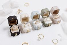 an assortment of rings and ring boxes on a white surface