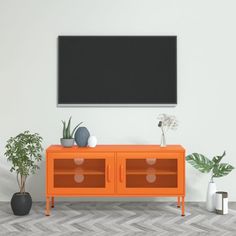 an orange entertainment center with two plants and a black screen mounted on the wall above it