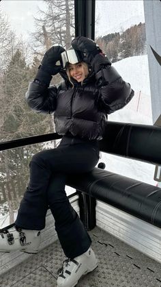 a woman sitting on top of a window sill in front of a ski slope