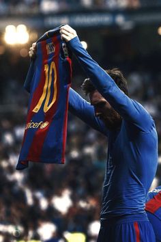 a man holding up a blue and red shirt in front of a crowd at a sporting event