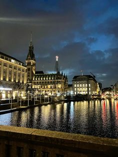 the city is lit up at night with lights reflecting in the water and buildings on both sides