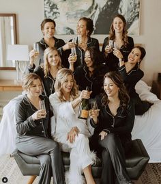 a group of women sitting on top of a bed holding wine glasses in their hands