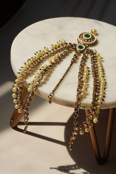 Experience the exquisite allure of our Kundan Mathapatti, a stunning blend of traditional elegance and contemporary charm. This gold-plated headpiece is adorned with vibrant green and gold Kundan stones, delicately complemented by faux pearls, offering a spectacular play of textures. Adjustable and versatile, this piece is perfect for any special occasion, enhancing your style and making an unforgettable statement. Key Features: Intricate Design: Exquisite gold-plated Mathapatti with hand-set vi Elegant Ceremonial Tikka With Tilla Detailing, Elegant Green Kundan Necklace With Latkans, Gold Tikka With Stone Work For Celebrations, Gold Cutdana Tikka For Reception, Elegant Gold Tikka For Festive Occasions, Ceremonial Festive Tilla Headpieces, Elegant Kundan Necklace With Latkans For Ceremonial Occasions, Gold Tikka With Stone Work For Festive, Gold Tikka With Stone Work For Festive Occasions