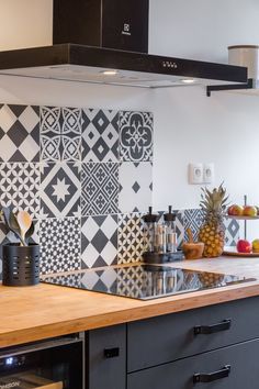 a kitchen with black and white tiles on the backsplash, stove hoods and counter tops