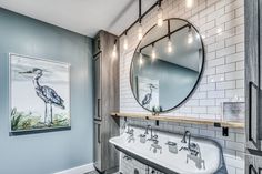 a bathroom with a sink, mirror and painting on the wall in it's corner