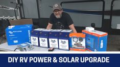 a man sitting at a table in front of some boxes with solar products on it