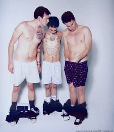 three shirtless men standing next to each other in shorts and socks with their feet on the ground