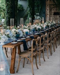 a long table is set up with blue and white flowers, candles, and napkins