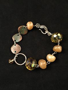 This fun bracelet has free form glass nugget beads, large faceted green glass beads, Greek metal discs (with a lovely patina, I might add) and sterling silver findings, clasp, and links. A single faceted yellow bead dangles from the artisan made sterling silver oversize link in the center of the bracelet. Eight inches long, including the s-hook clasp. Bohemian Czech Glass Crystal Bracelet With Faceted Beads, Bohemian Crystal Bracelet With Czech Glass Faceted Beads, Bohemian Faceted Crystal Bracelet With Round Beads, Adjustable Czech Glass Jewelry Bracelet, Bohemian Bracelet With Faceted Beads, Yellow Faceted Beads Bracelet, Faceted Czech Glass Bracelets As Gift, Bohemian Czech Glass Crystal Bracelet, Amber Colored Nickel Free Czech Glass Jewelry