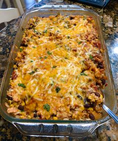 a casserole dish with chicken, beans and cheese on it sitting on a kitchen counter