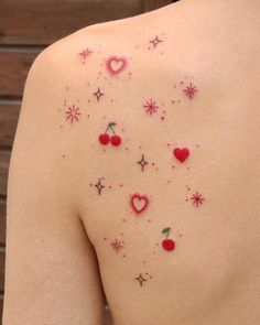 the back of a woman's shoulder with small tattoos on it