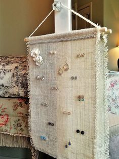 a wall hanging made out of burlap with earrings attached to it and a lamp in the background