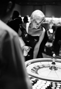 black and white photograph of a woman in front of a spinning roule at a casino