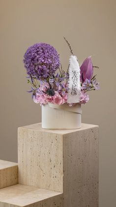 a white vase with purple flowers on top of it