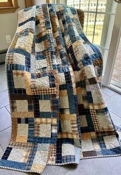 a large blue and tan quilt sitting on top of a floor next to a window