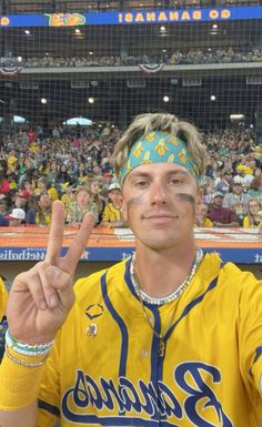 a man in a baseball uniform is making the peace sign with his hand at a game