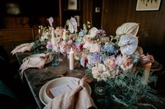 the table is set with candles, flowers and napkins for guests to sit at