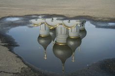 the reflection of two buildings in a puddle on the ground with no one around it