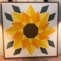 a yellow and brown paper sunflower sitting on top of a wooden table next to a clock