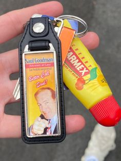 a hand holding a keychain with an advertisement on it and a tube of toothpaste