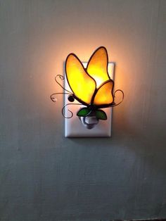 a light that is on the side of a wall with a flower in front of it