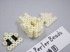 three pieces of white and black bead next to a sign that says perler beads