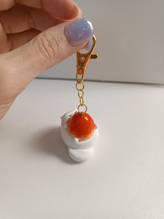 a hand holding a keychain with an orange and white object on it